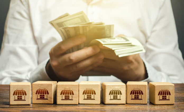 Blocks,Symbolizing,Business,Network,And,Businessman,Counting,Money.,High,Income Person counting cash with wooden blocks depicting store icons