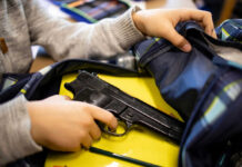 Mom’s Gift, School Attack – Who Pays? Kid placing handgun inside a backpack on desk