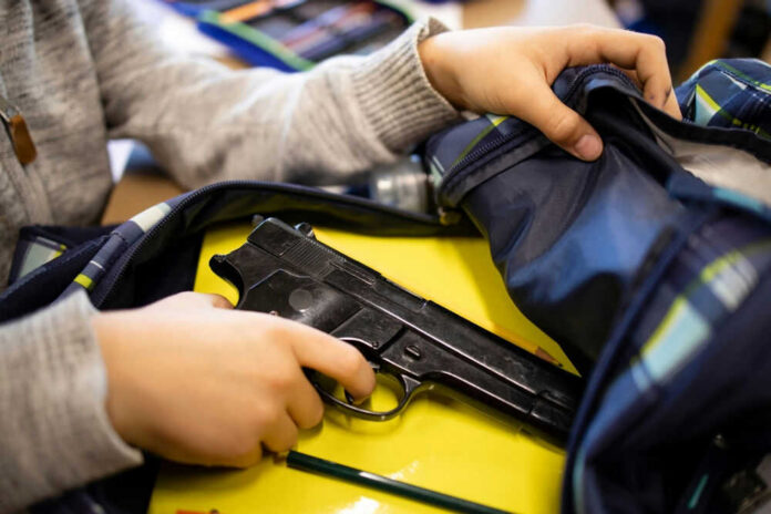 Kid placing handgun inside a backpack on desk