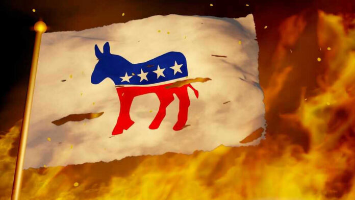 shutterstock_2206000525 Torn Democratic flag burning amid flames and embers.