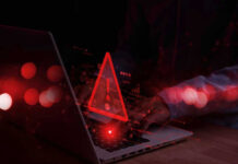 Warning symbol over laptop with user.