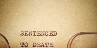 Typewriter typing the phrase 'Sentenced to Death' on aged paper