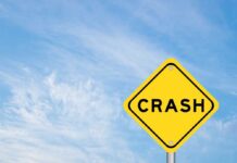 Yellow warning sign reading crash against blue sky