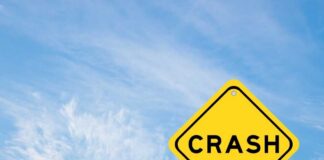 Yellow warning sign reading crash against blue sky