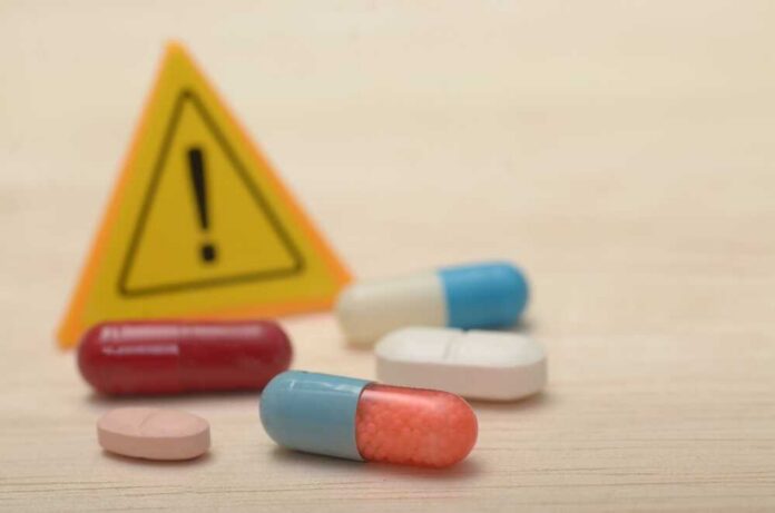 Pills with warning sign in background