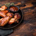 Sweet-And-Sour Wings Spark Outrage Online Chicken wings with barbecue sauce on a black plate