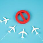 Chaos Turns Nation Into No-Fly Trap A red prohibition sign surrounded by white airplane models on a blue background