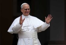 Clergyman in white robes raising both hands