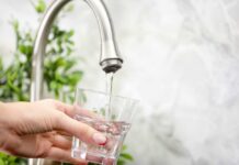 Longevity Drinks Exposed: Just Three Hand holding a glass under a kitchen faucet as water pours in