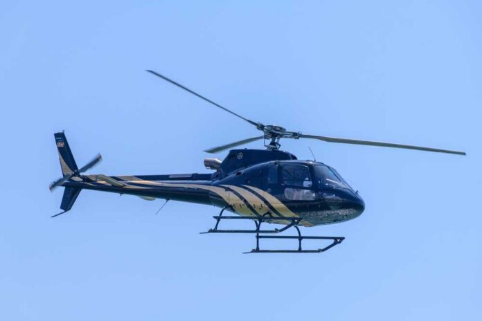 A helicopter flying against a clear blue sky