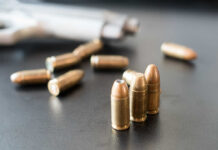 Superstar’s Home Riddled By Bullets – Nursery Hit Close-up of bullets on a dark surface with a handgun in the background