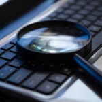 Terrifying Clue Hiding In Your Voice Magnifying glass on a laptop keyboard.