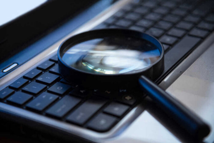 shutterstock_494287042 Magnifying glass on a laptop keyboard.