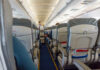 WATCH: Celebrity Goes CRAZY Midair Airplane cabin aisle with rows of seats and a flight attendant pushing a service cart